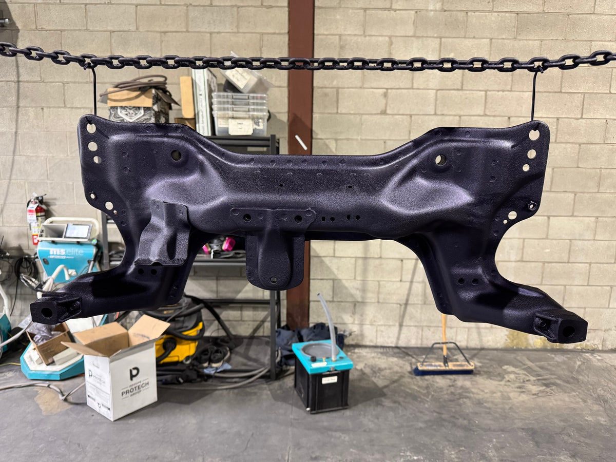 Car subframe powder coated in black hanging in the shop