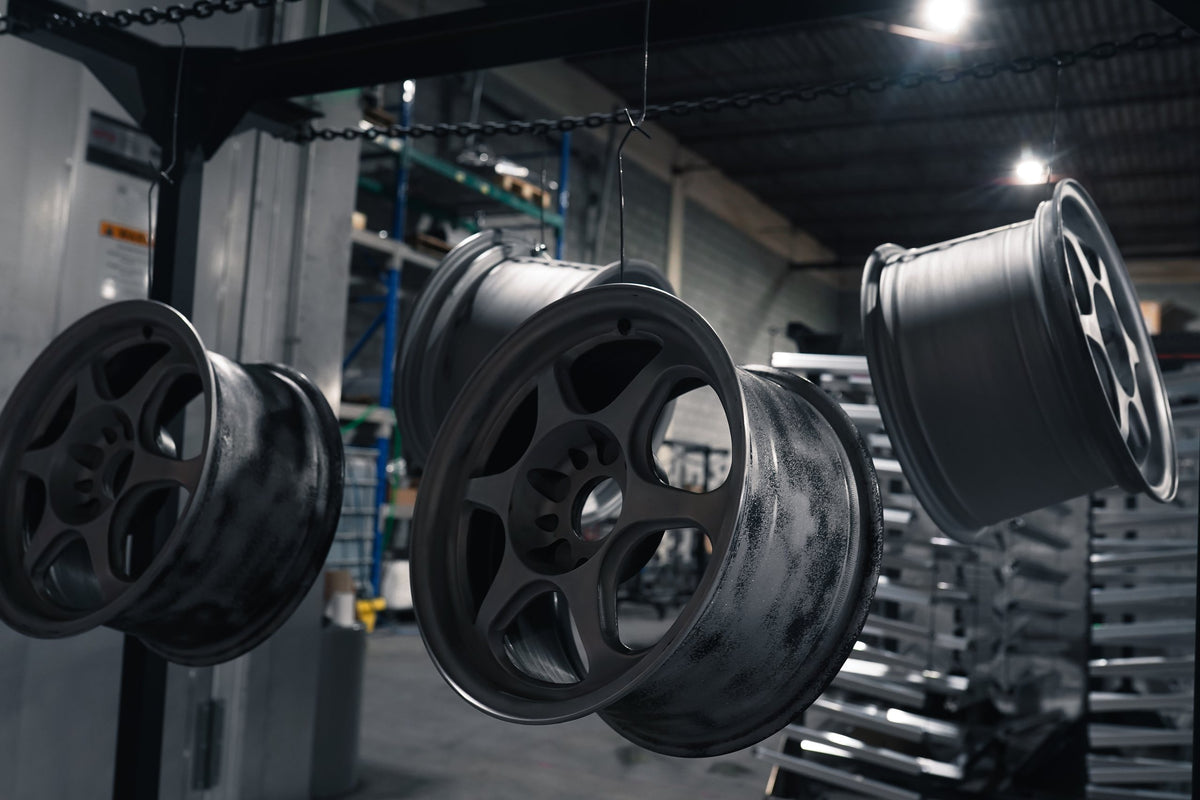Wheels powder coated in matte black hanging in the shop