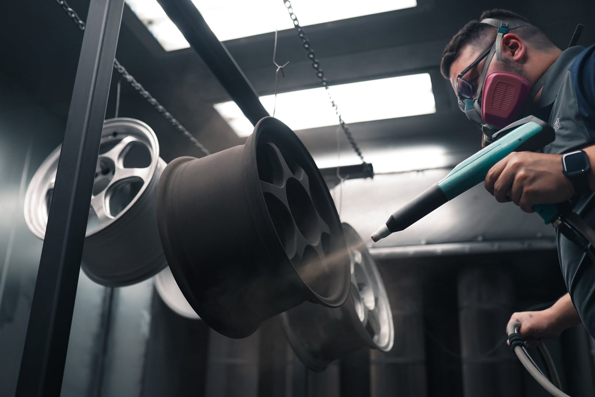 Painter applying bronze powder to a wheel with an electrostatic gun