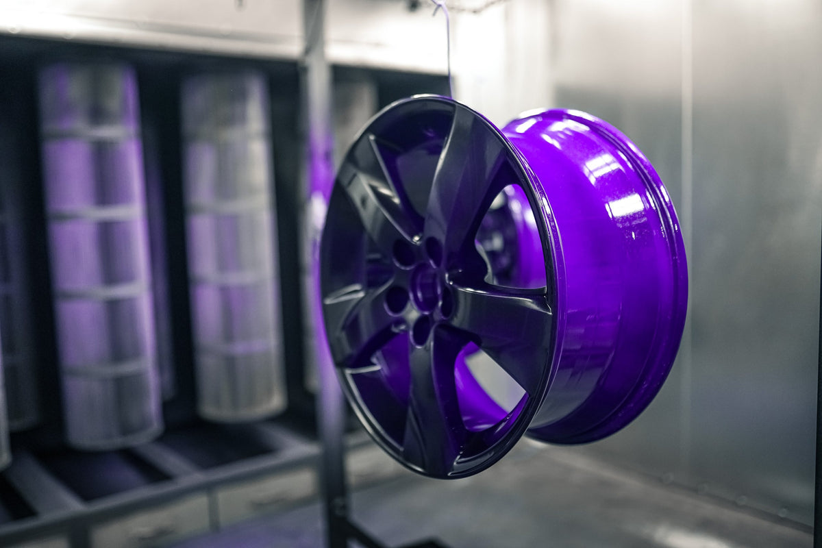 Wheel powder coated in gloss purple hanging in the booth in front of the filters
