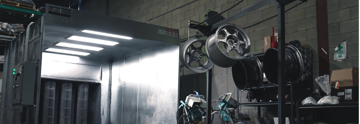 Lit powder coating booth with wheels hanging beside it
