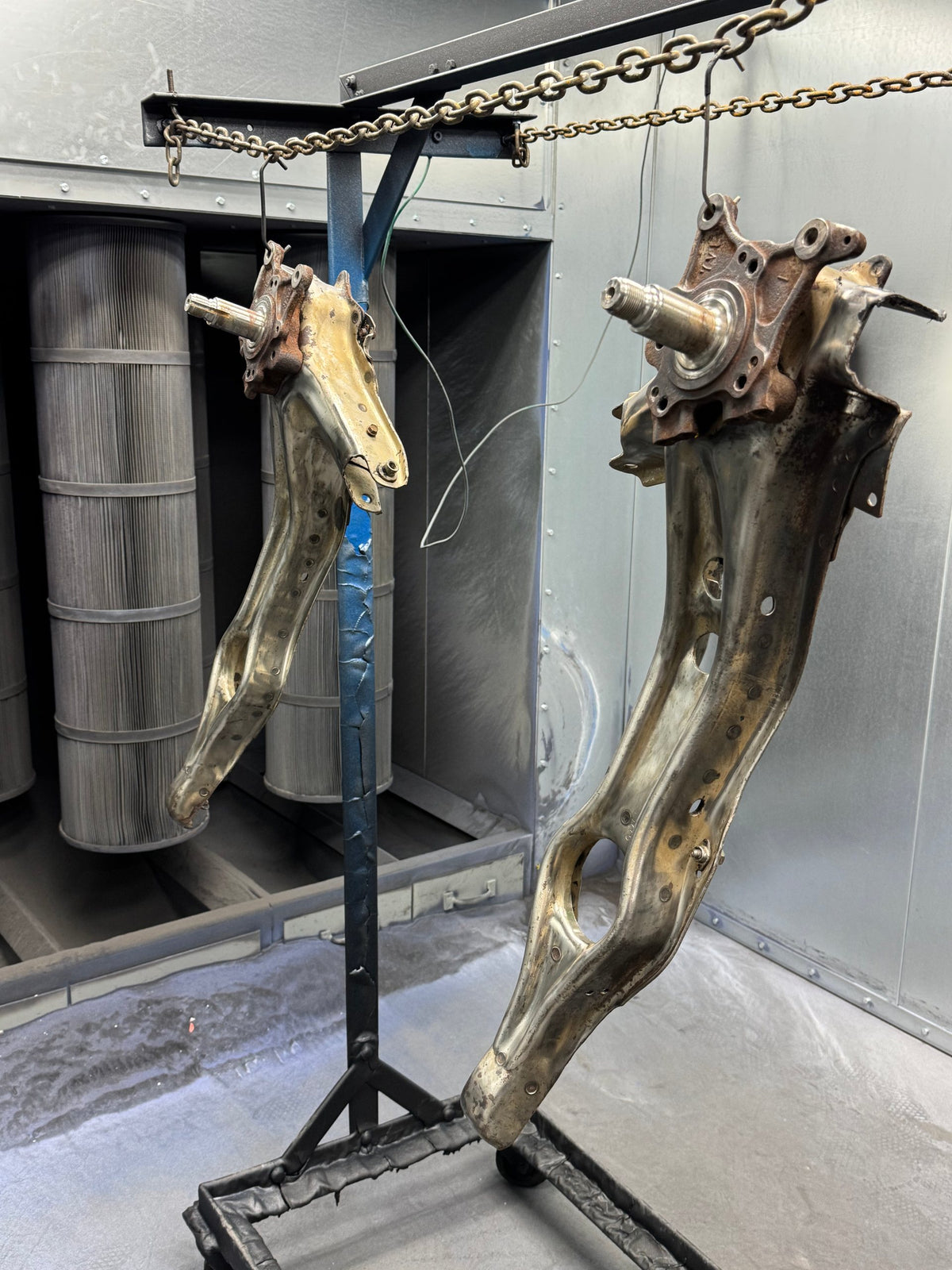 Rusty suspension parts hanging in the booth before stripping
