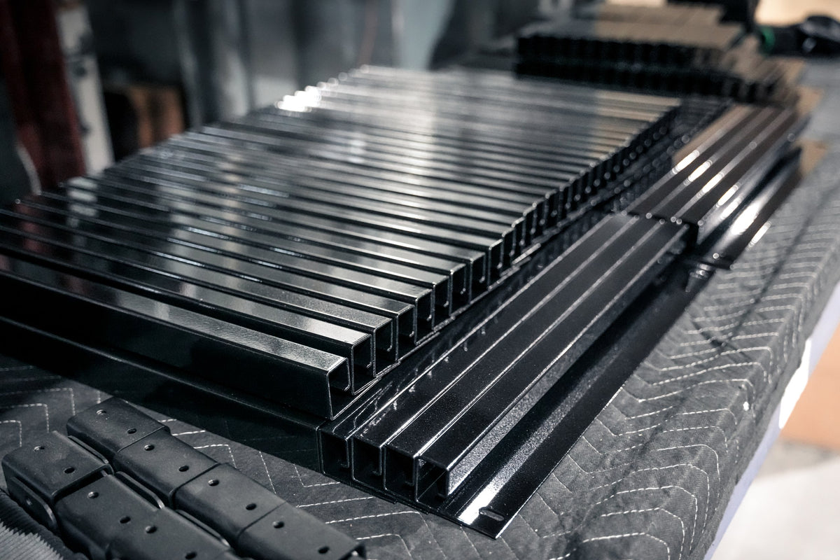 Steel tubes powder coated in gloss black lined up on a table