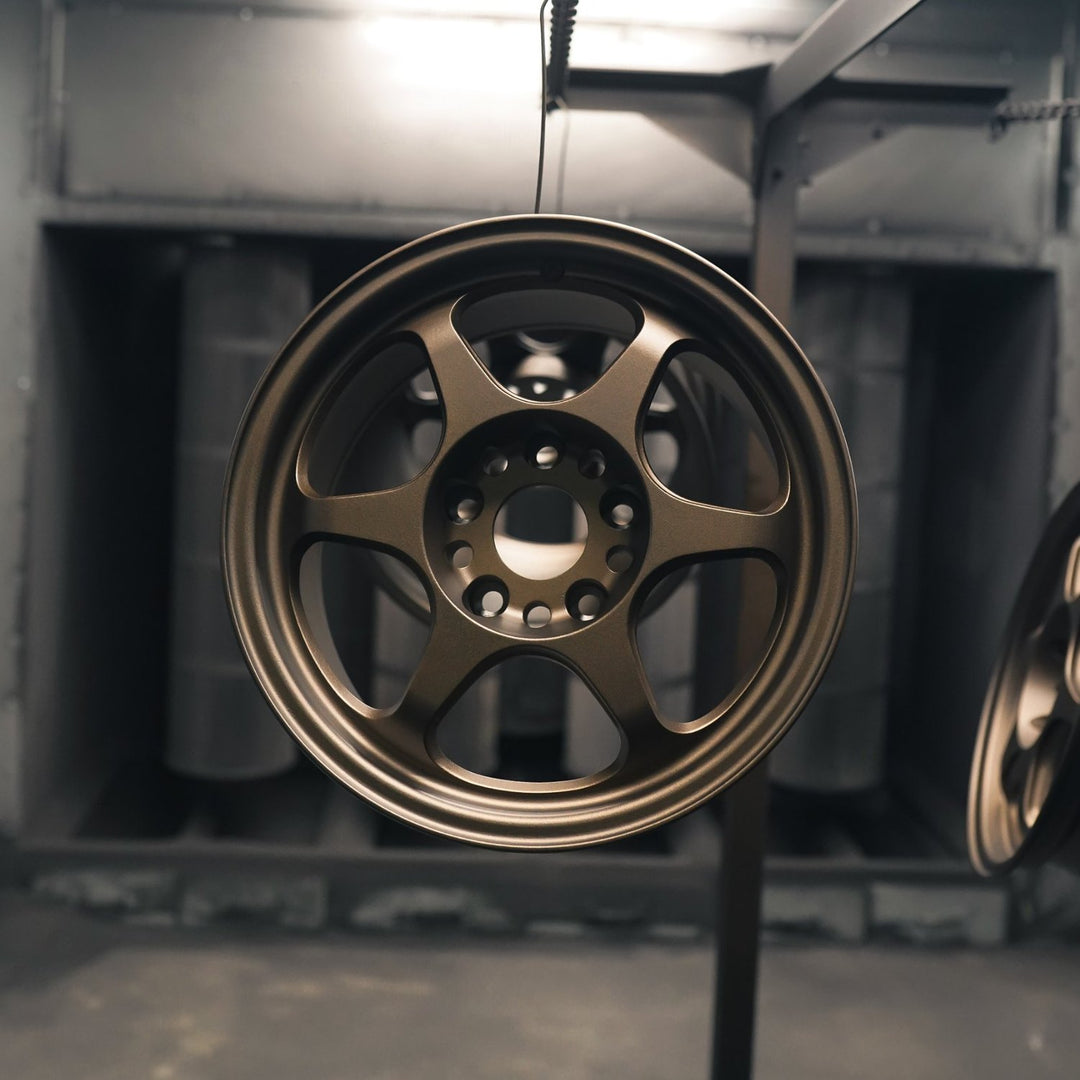 Front view of a six-spoke wheel powder coated in matte bronze in the booth