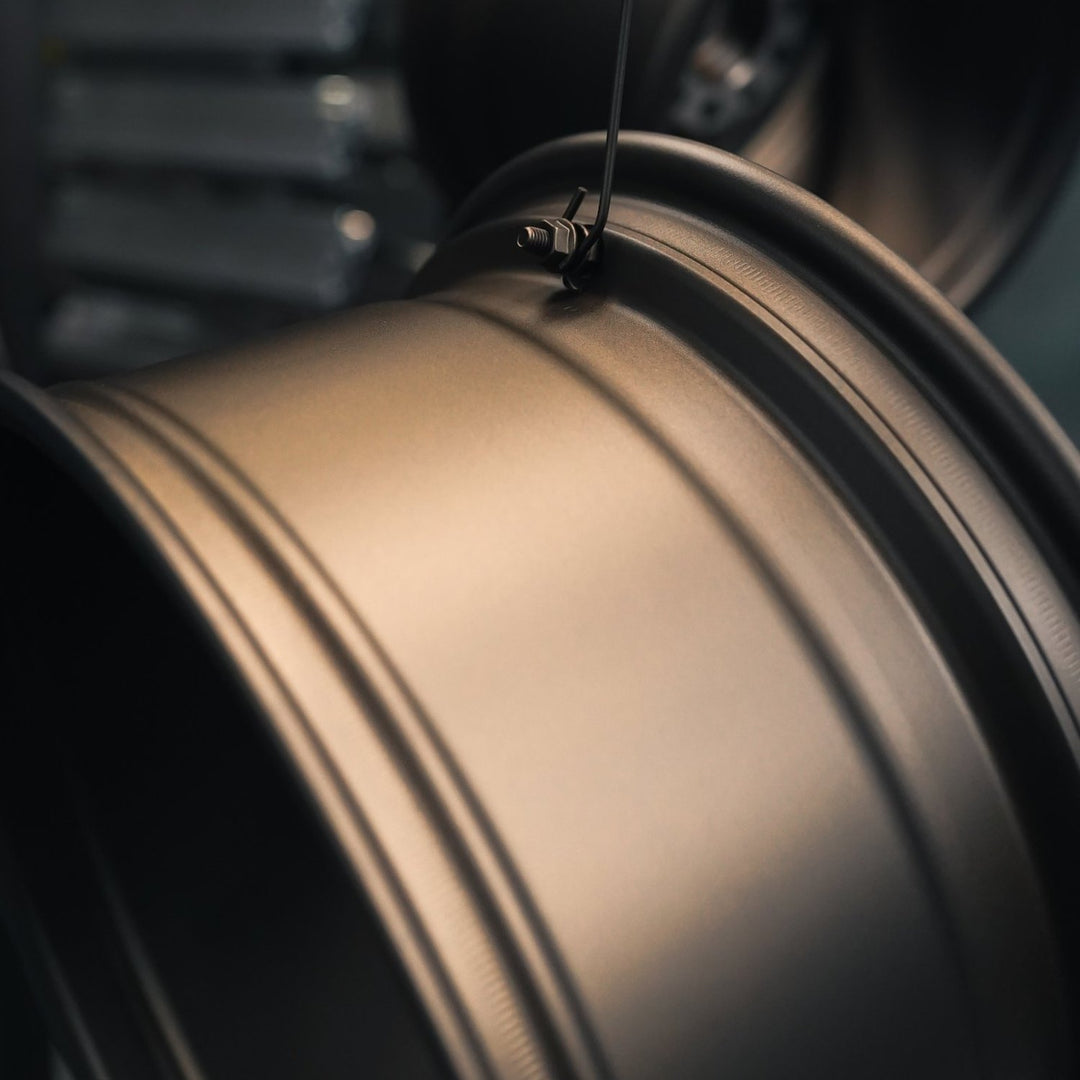 Rim edge of a wheel powder coated in matte bronze, hanging from a hook