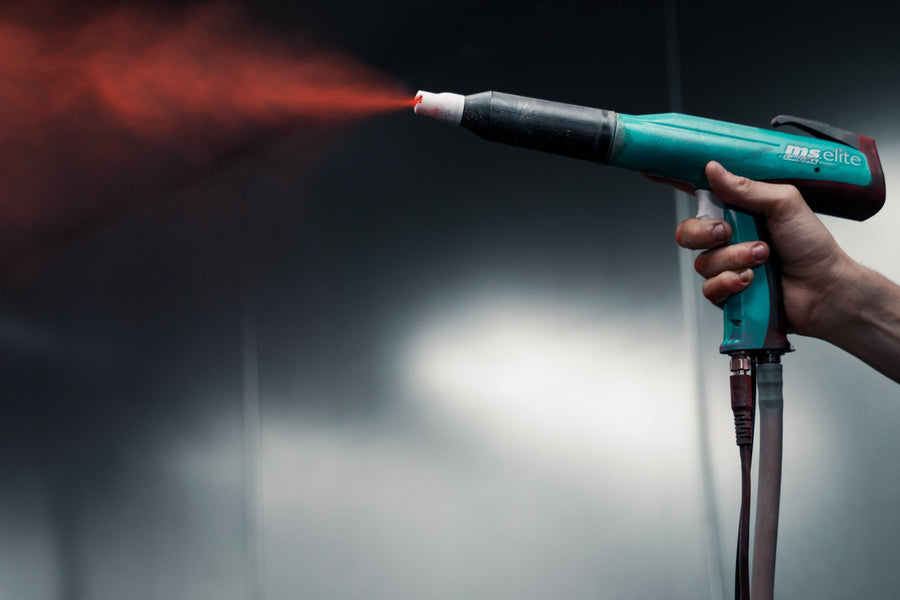 Electrostatic powder coating gun spraying a cloud of red powder
