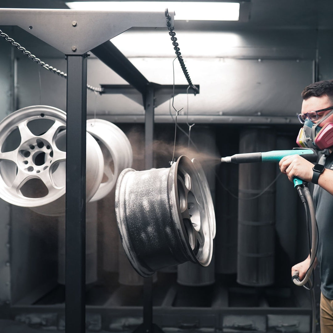 Painter applying powder to a stripped wheel in the booth