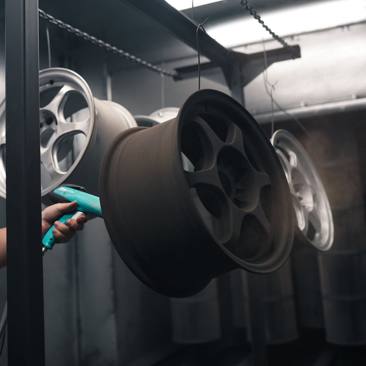 Bronze powder being applied to a wheel with an electrostatic gun