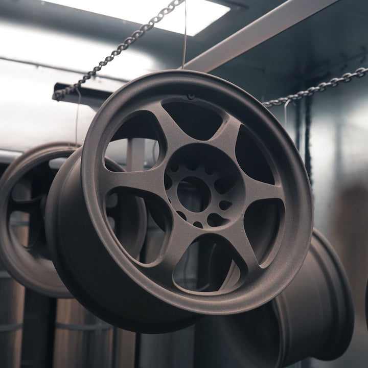 Wheels powder coated in matte bronze hanging from chains in the booth