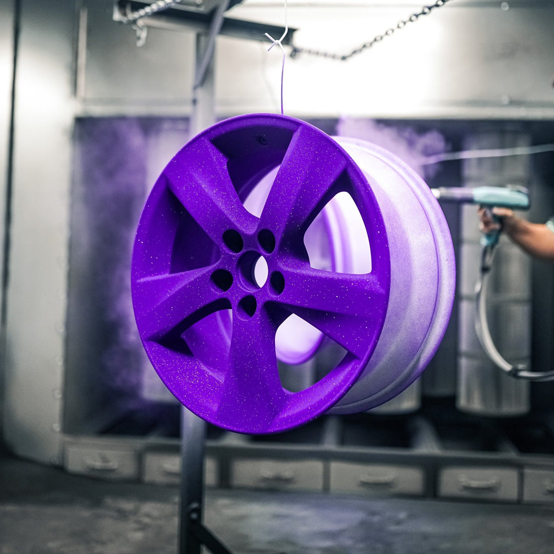 Wheel covered in purple powder before curing, in the booth