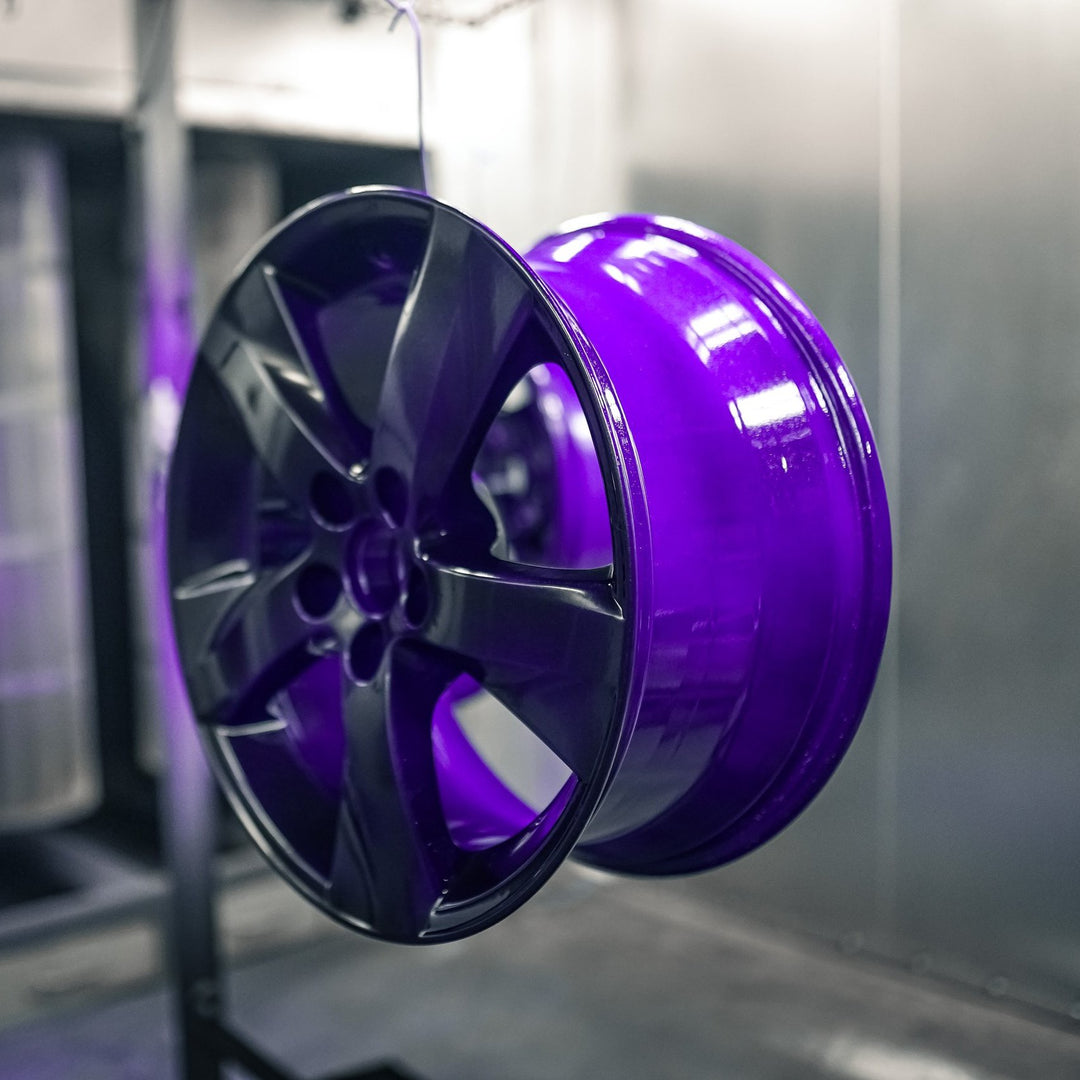 Wheel powder coated in gloss purple hanging in the booth