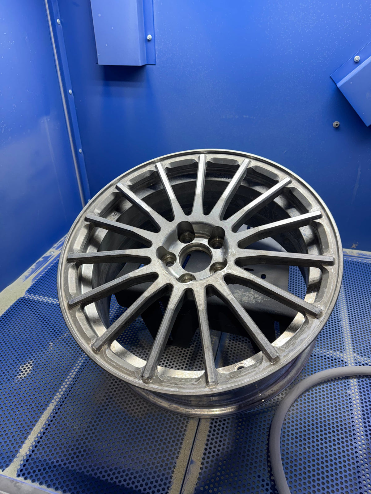 Aluminum wheel blasted down to bare metal, sitting in the blast cabinet
